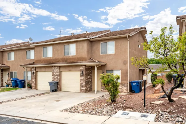 Two-story stucco exterior with brick accents, attached two-car garage, and tiled roof
