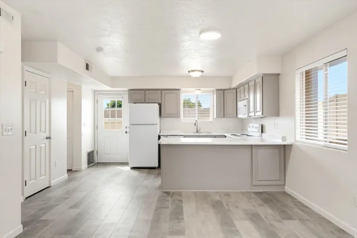 Kitchen featuring gray cabinetry, white appliances, white countertops, and wood-finish flooring