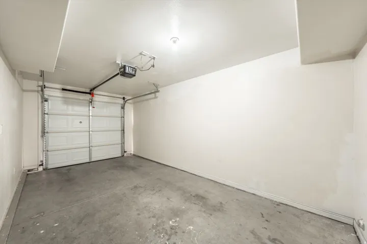 Single-car garage with a panel garage door, concrete flooring, and an overhead garage door opener
