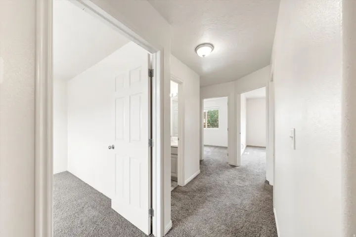 Hallway with light gray carpet flooring and white painted walls