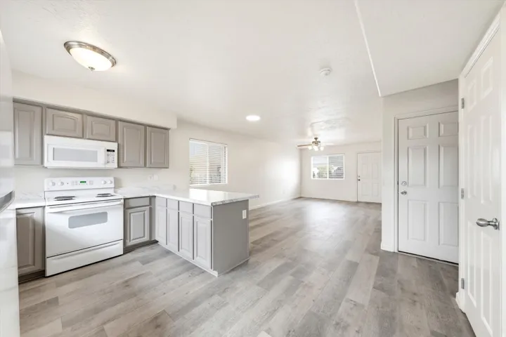 Kitchen with gray cabinetry, white appliances, and light-toned countertops