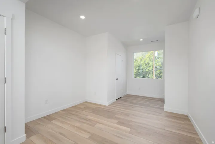 Recessed lighting, wood-finish flooring, white walls, and a window with exterior scenery