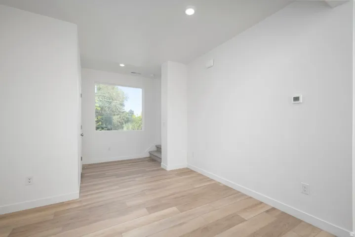Light-toned wood-finish flooring, white walls, recessed ceiling lighting, and a large window
