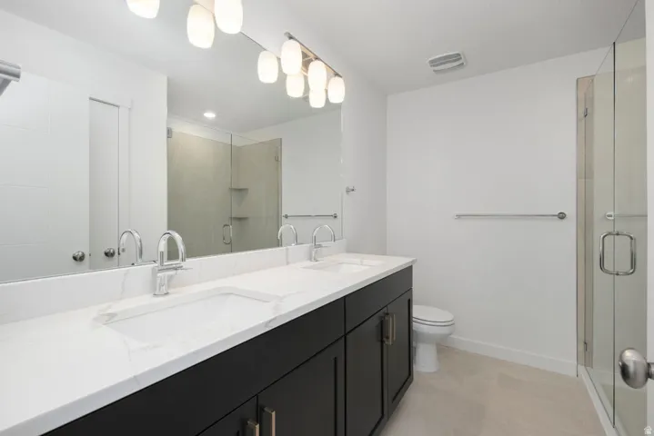 Dual vanity with undermount sinks, stone-finish countertop, dark wood-finish cabinetry, and chrome fixtures