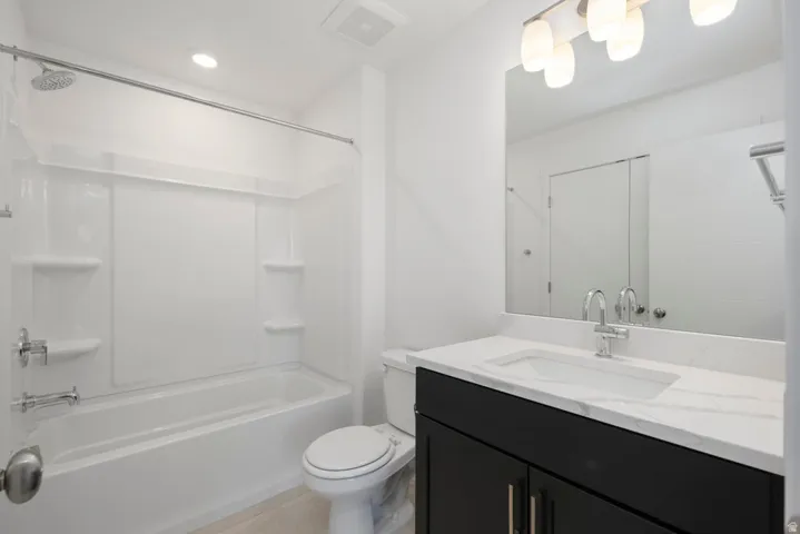 White bathtub with integrated shower, single-handle faucet, and built-in shelving