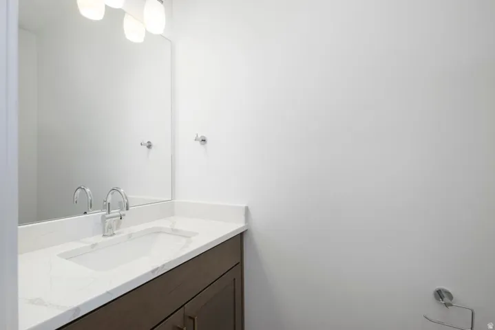 Single vanity with a white countertop and integrated sink, chrome faucet, and wood-finish cabinetry