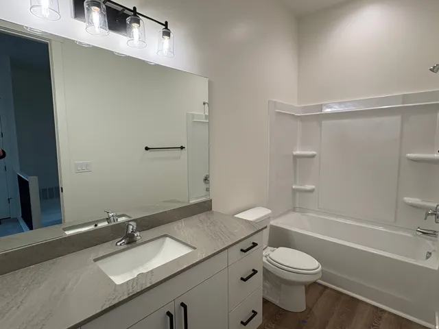 Bathroom featuring a single vanity with an integrated sink, stone-finish countertop, and white cabinetry