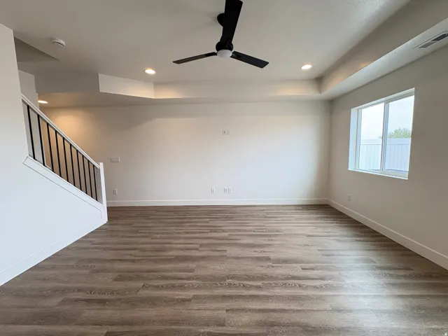Wood-finish flooring, white walls, and a black ceiling fan with recessed lighting