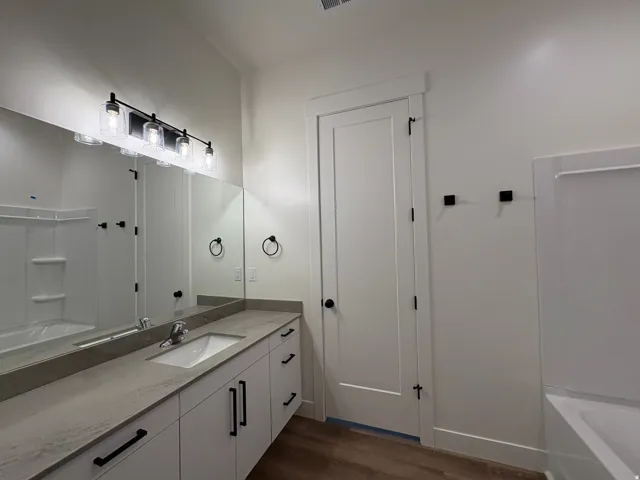White vanity with integrated sink, stone-finish countertop, and black hardware