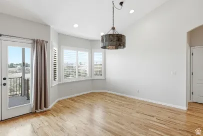 Wood-finish flooring, vaulted ceiling, recessed lighting, bay window with plantation shutters, and a private balcony