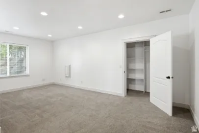 Recessed lighting, carpet flooring, a window with blinds, a built-in closet with shelving, and a panel door