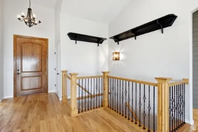 Wood-finish flooring with a wooden entry door and staircase featuring a wrought iron balustrade