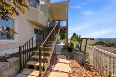 Two-story stucco exterior with multiple windows, leading to an upper-level covered deck