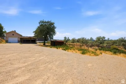 Gravel driveway with extensive parking, attached garage, and covered carport structure