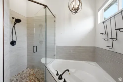 Corner soaking tub, glass-enclosed shower with pebble-tile flooring, and a rainfall showerhead