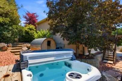 Outdoor spa, wood deck, barrel sauna, stone retaining wall, and mature landscaping