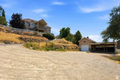 Private gravel driveway with a detached garage and an extended carport