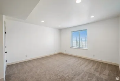 Bright, freshly painted bedroom with recessed ceiling lighting, neutral wall finishes, and plush carpeting throughout