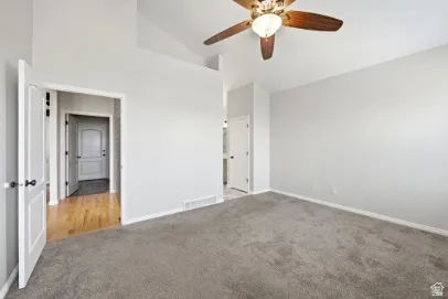 Vaulted ceiling with a ceiling fan, neutral wall paint, and gray carpet