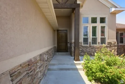 Stucco exterior with stone accent, wood-finish entry door, and multi-pane windows