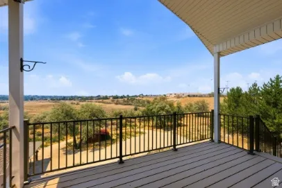 Covered outdoor deck with composite decking and black metal railings, offering expansive landscape scenery