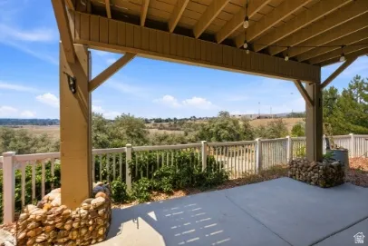 Covered patio with concrete flooring, wood beam structure, and string lighting