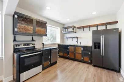 Kitchen featuring wood-finish flooring, stainless steel appliances, industrial-style cabinetry, and recessed lighting