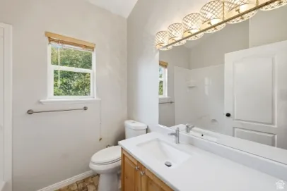 Bathroom featuring a single-sink vanity, light wood cabinetry, white countertop, and tiled flooring