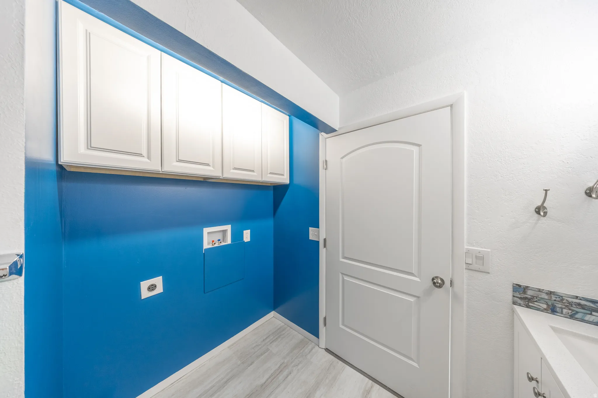 White shaker-style cabinetry, arched panel interior door, and wood-finish flooring