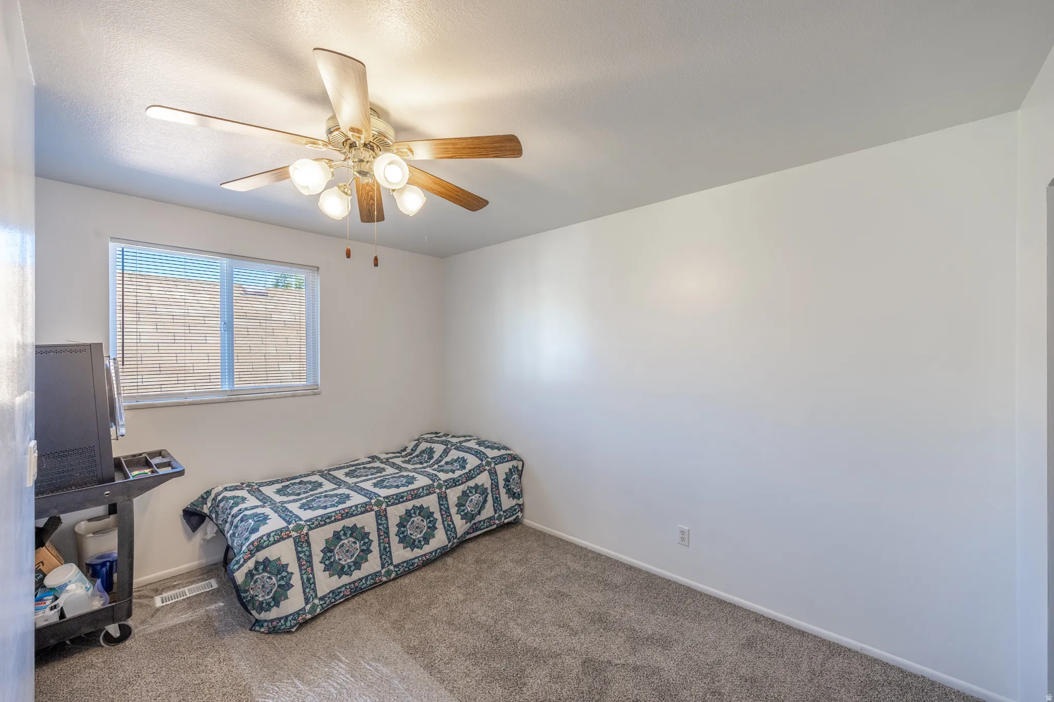 Neutral wall finishes, textured carpeting, and a ceiling fan with integrated lighting