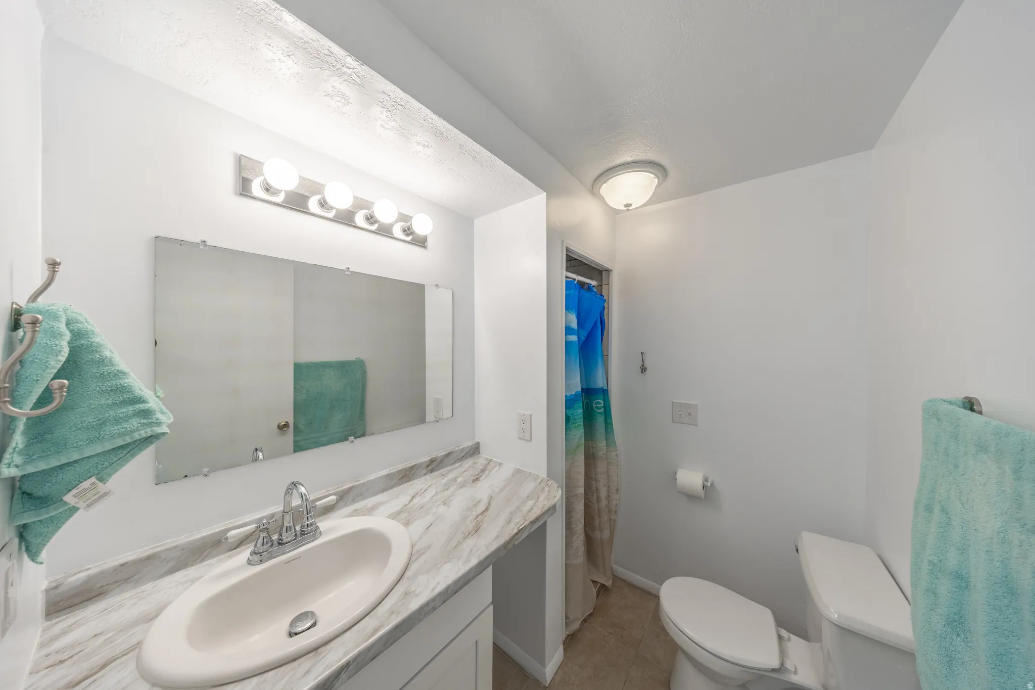 Vanity with a single basin sink, laminate countertop, and overhead lighting