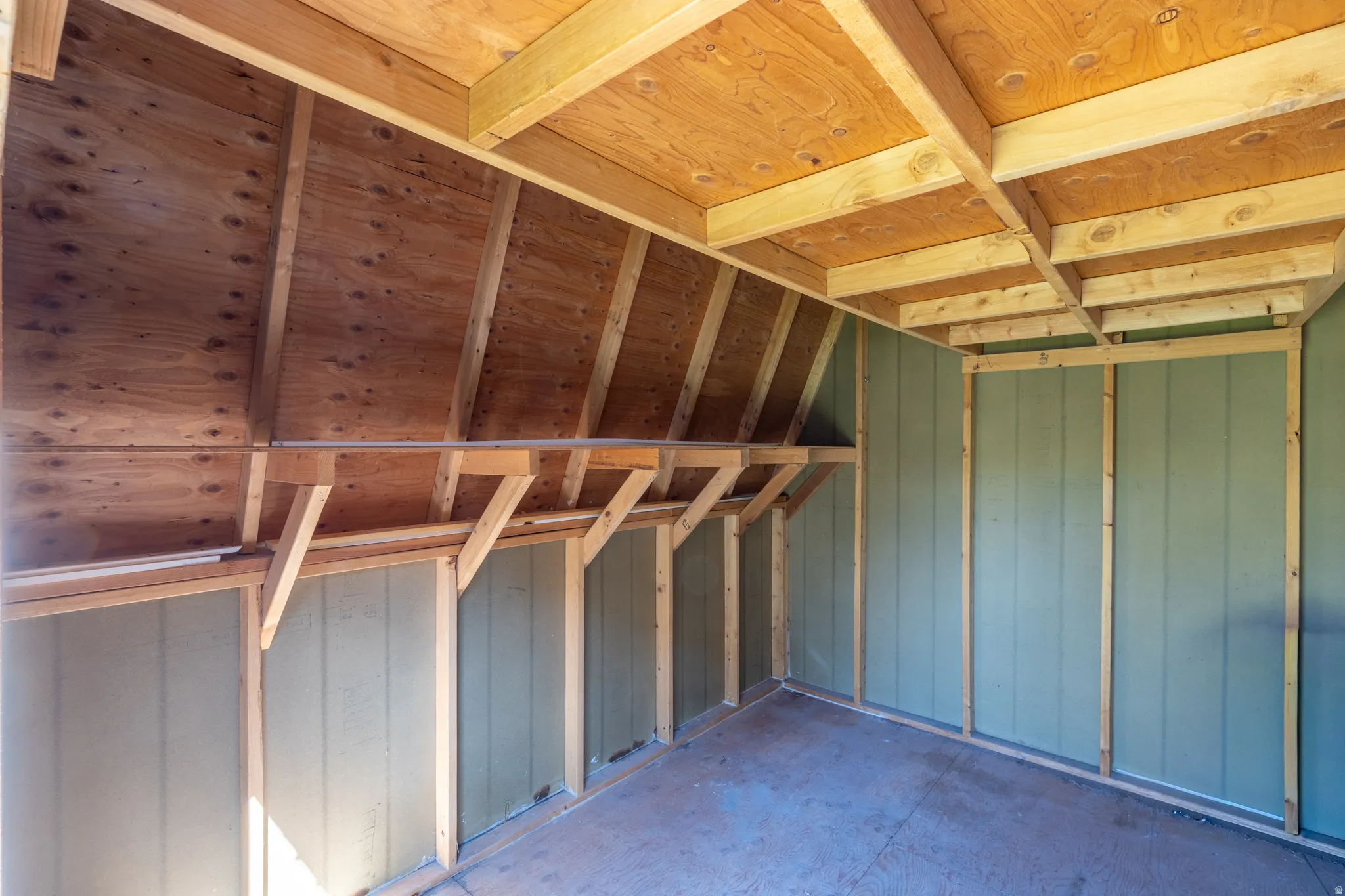 Exposed wood beam ceiling, wood-finish flooring, and light green panel walls