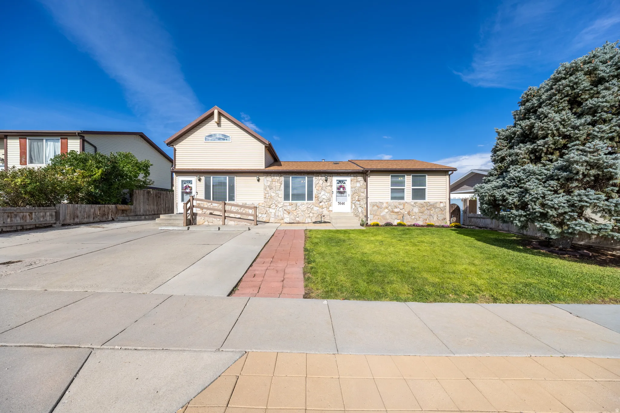 Stone veneer exterior featuring a gabled roofline and front lawn