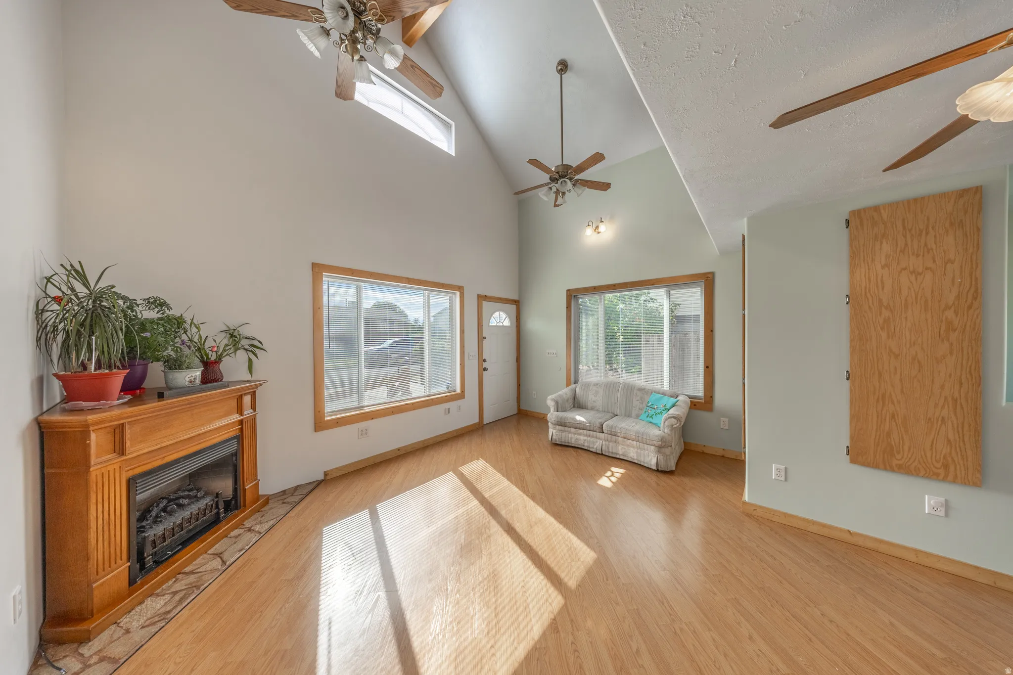 Vaulted ceilings, wood-finish flooring, and a corner fireplace with a wood-finish mantel