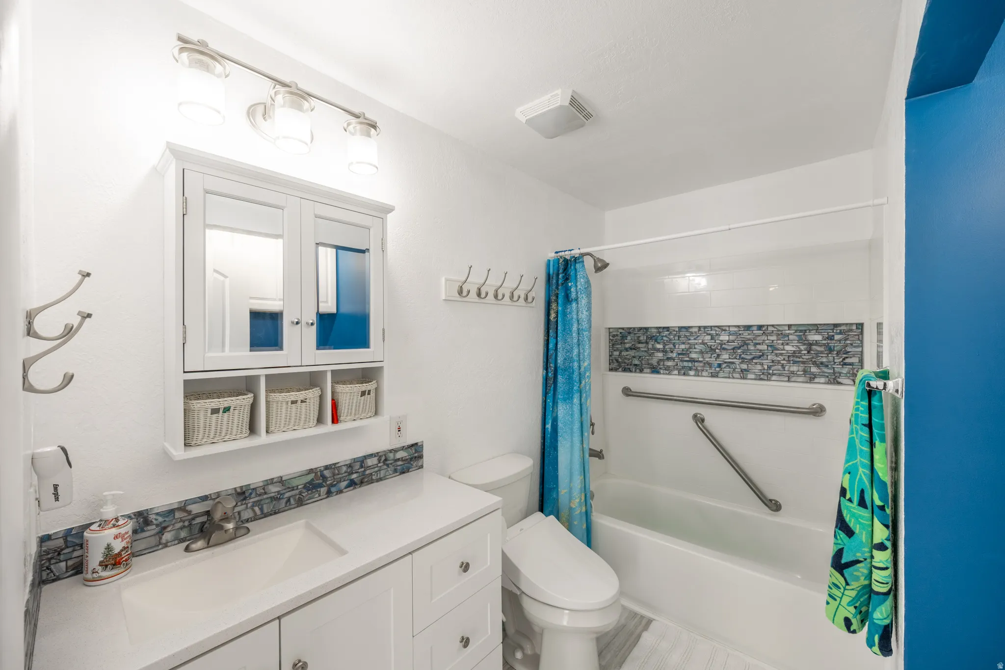 White vanity with integrated sink, mosaic tile backsplash, and mirrored medicine cabinet