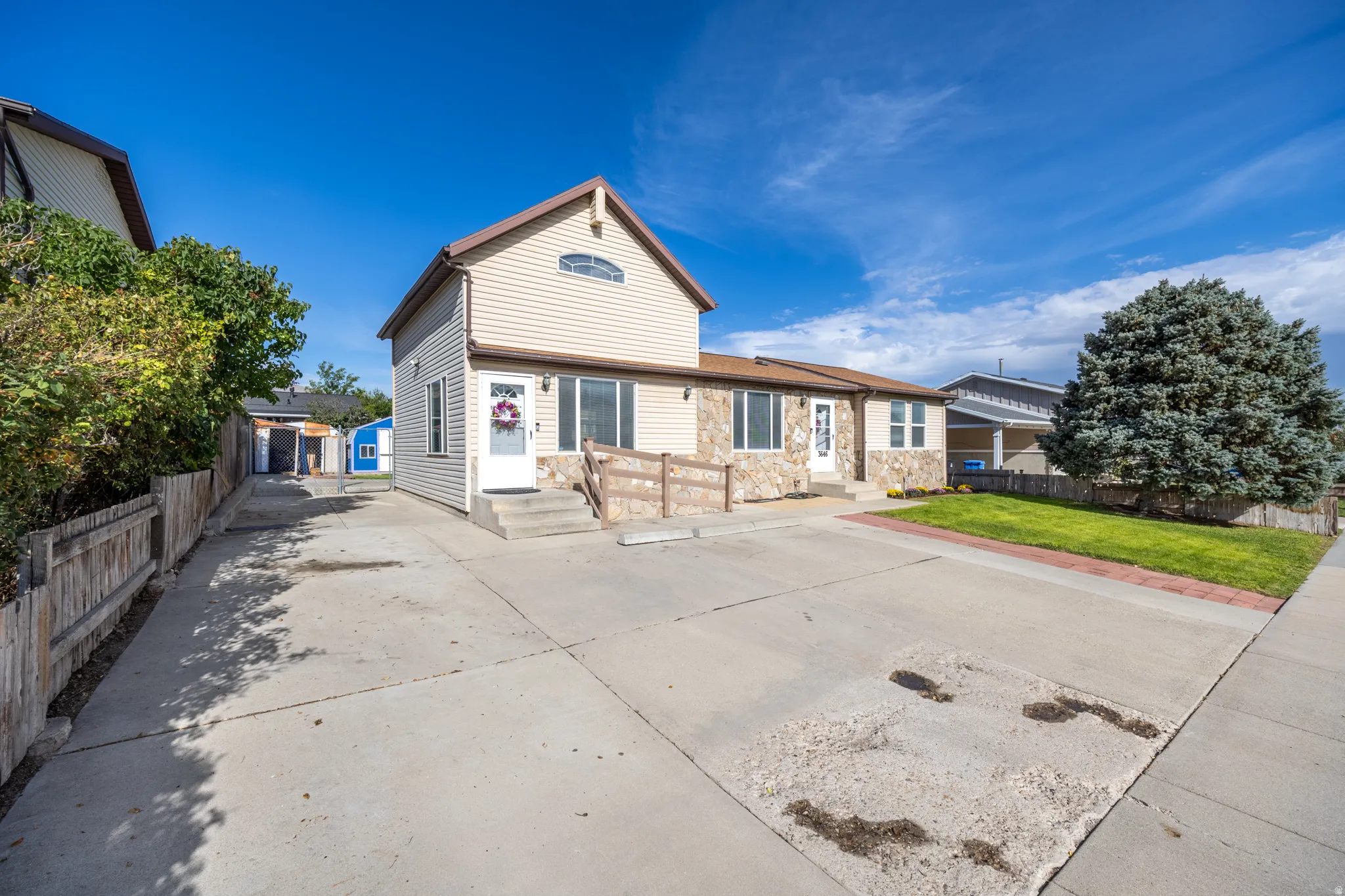 Exterior with stone and siding facade, concrete driveway, and established landscaping