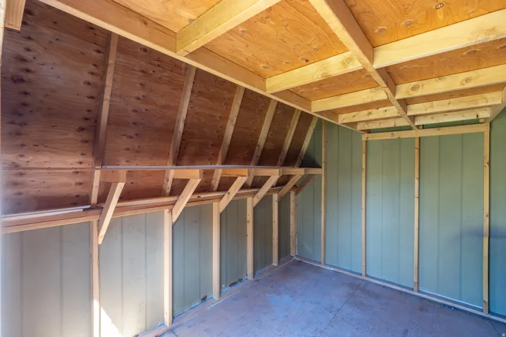 Exposed wood beam ceiling, wood-finish flooring, and light green panel walls