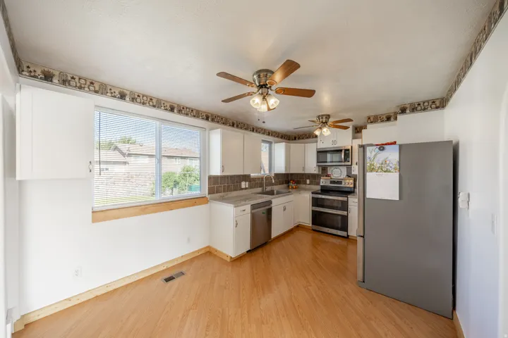 Kitchen featuring wood-finish flooring, white cabinetry, integrated stainless steel dishwasher, and a stainless steel oven/range