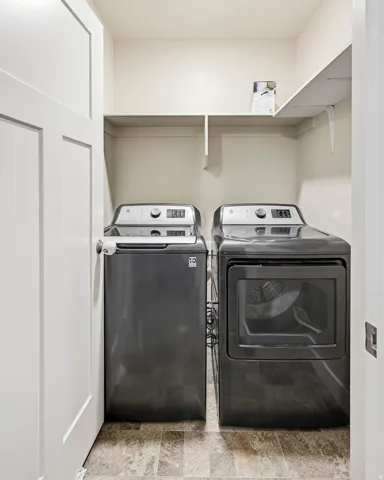Laundry area featuring a side-by-side washer and dryer, built-in shelving, and light-toned walls
