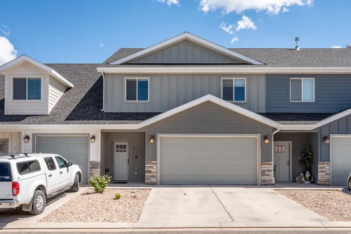 Multi-level exterior with dormer windows, garage access, and stone-accented columns