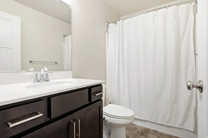 Vanity with white countertop, undermount sink, chrome faucet, and dark wood-finish cabinetry