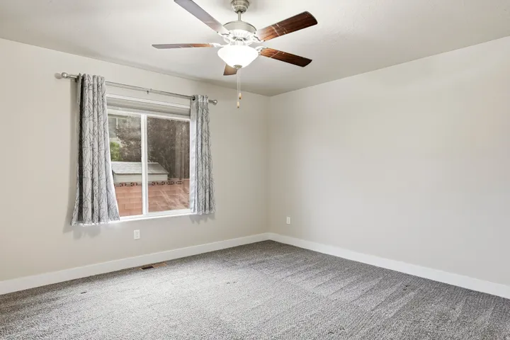 Neutral-toned walls, ceiling-mounted fan with integrated lighting, and a window with white trim