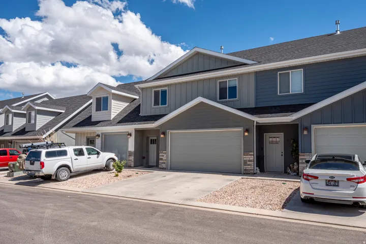 Modern townhome exterior with mixed siding, stone accents, and an attached single-car garage