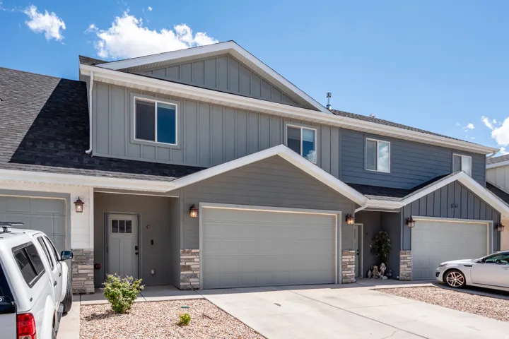 Contemporary townhouse exterior featuring vertical siding, attached garages, stone accents, and a covered entry