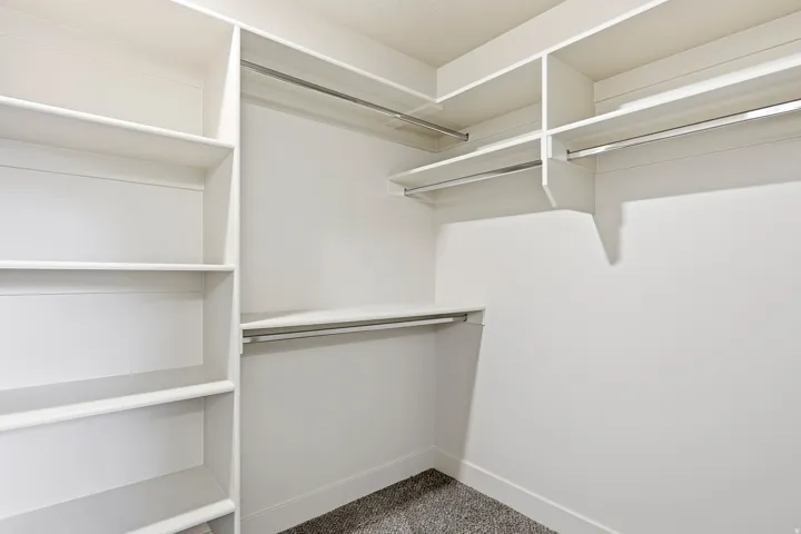 Built-in shelving, multiple hanging rods, and dark gray carpeting