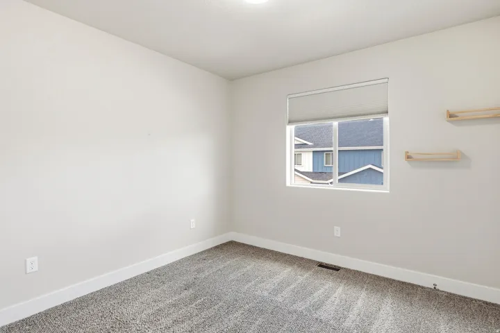 Wall-to-wall carpeting, neutral wall finishes, and a single window with roller shade