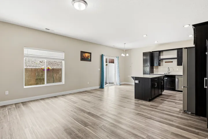 Recessed lighting, wood-finish flooring, dark wood cabinetry, stainless steel appliances, and a kitchen island with seating