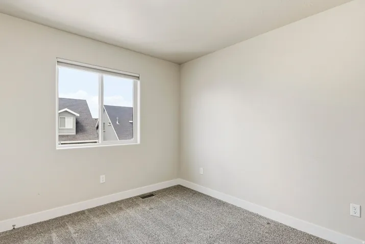 Neutral wall paint, gray carpet, single window with white trim, baseboard molding, and electrical outlets
