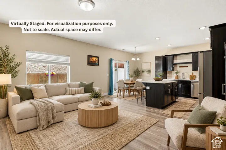 Open-concept living area featuring wood-finish flooring, recessed lighting, and a kitchen with dark cabinetry and stainless steel appliances