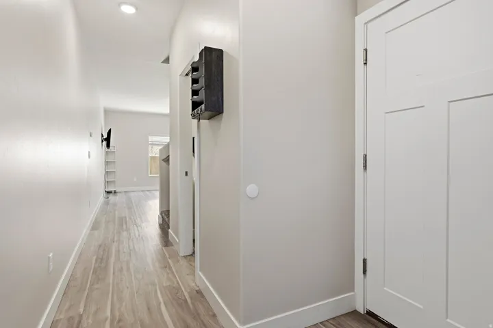Recessed ceiling lighting illuminates a hallway with wood-finish flooring